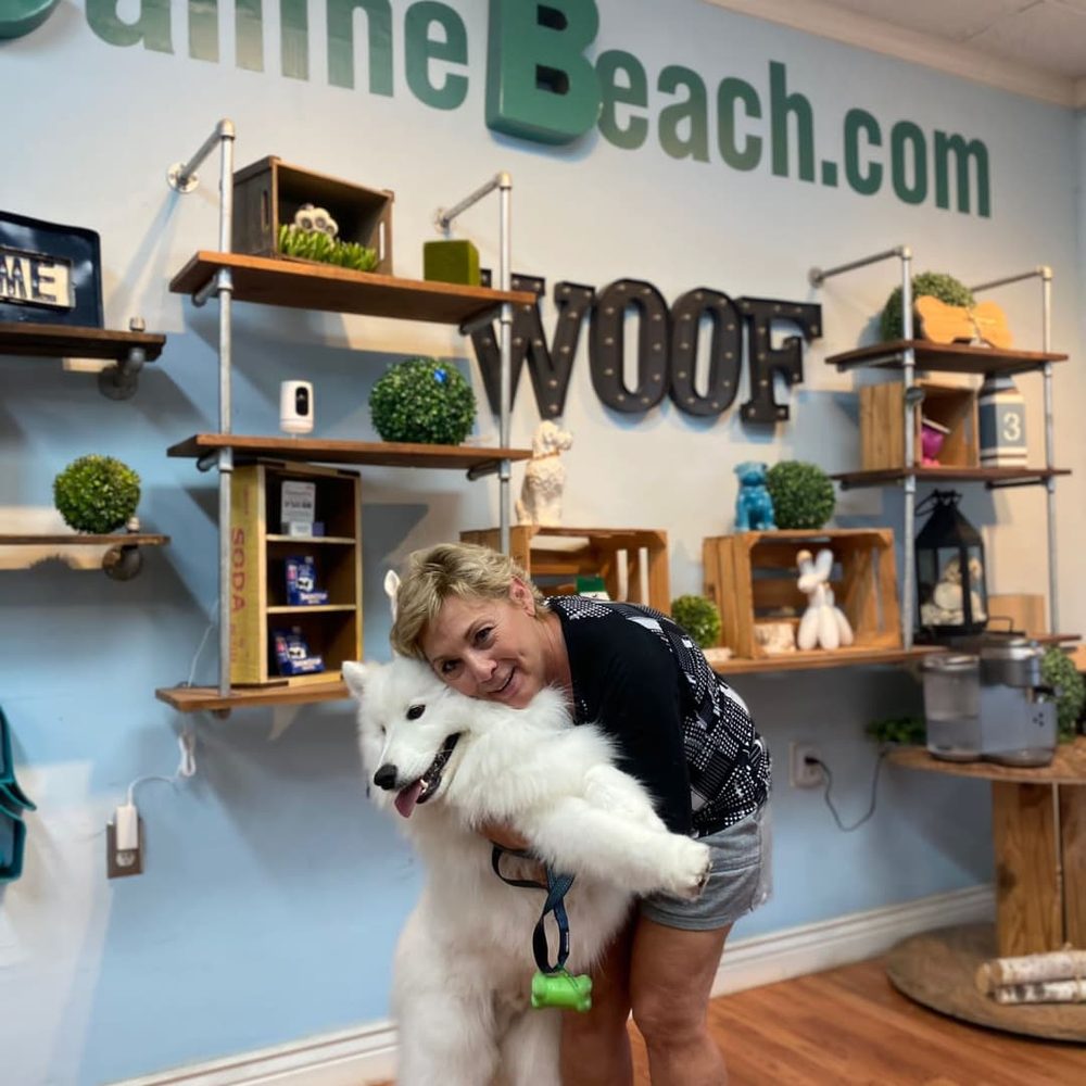Owner Gio hugging a freshly groomed Samoyed at the salon